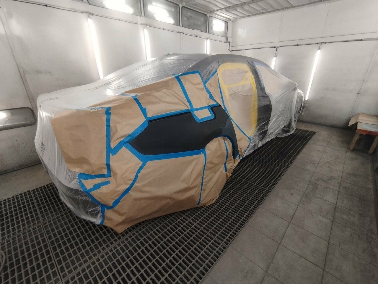 Автомобиль, укрытый плёнкой и бумагой, в покрасочной камере